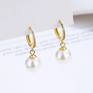 Macro detail of 925 silver shell pearl earrings with pavé zircon settings on gold hoops