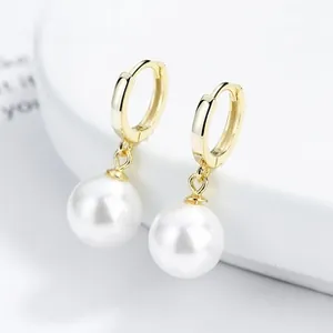 Macro detail of 925 silver pearl drop earrings with elegant gold hoop closure