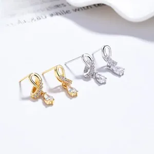 Detailed view of silver and gold teardrop earrings with pavé stones and zircon pendants