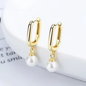 Close-up of U-shaped gold plated hoop earrings with white round hanging pearls