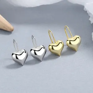 Detailed macro view of 3D heart-shaped earrings in polished gold and silver finishes