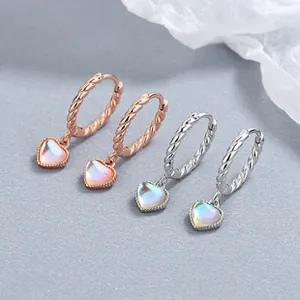 Detail of twisted hoop earrings with heart-shaped iridescent opal pendants in silver and rose gold