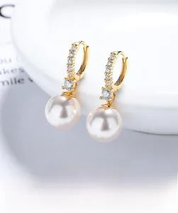 Macro shot of gold-plated hoop earrings with micro-inlaid zircon and a white pearl drop
