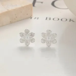 Macro view of flower stud earrings featuring matte silver finish and beaded centers