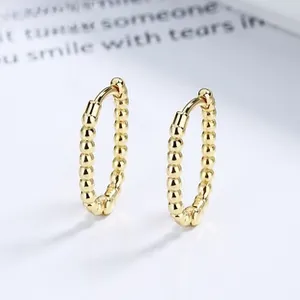 Macro view of gold beaded hoop earrings featuring a polished spherical textured design
