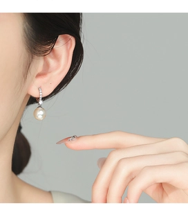 Detailed view of sterling silver earrings featuring round pearls and micro-set cubic zirconia