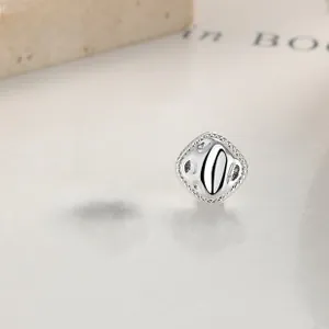 Macro detail of square silver stud earrings featuring hammered finish and woven edges