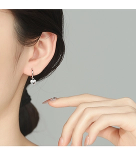 Dettaglio degli orecchini a cuore in argento indossati da una modella dal design sobrio