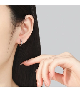Close-up of minimalist 925 silver hoop earrings with sparkling zircon on female ear