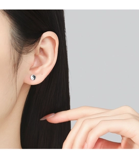 Close-up of a model wearing the sterling silver Tai Chi yin yang stud earring in a side view