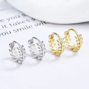 Detail of silver and gold olive leaf earrings with intricate textures on white background