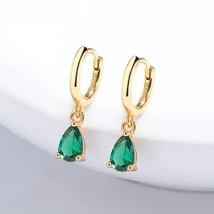 Macro shot of 925 silver gold-plated hoop earrings with pear-cut emerald green zircons