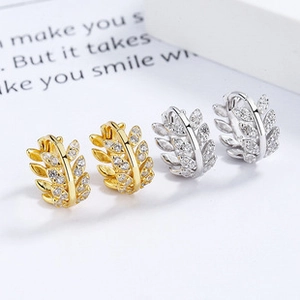 Macro detail of leaf-shaped hoop earrings with sparkling cubic zirconia in gold and silver