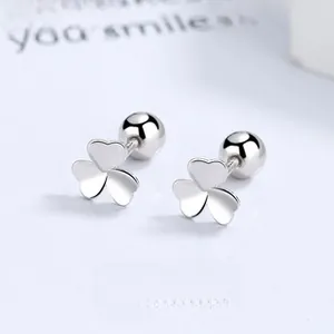 Macro detail of silver clover earrings with screw back design on minimalist backdrop