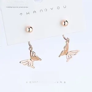 Macro detail of rose gold hollow butterfly stud earrings on a display card