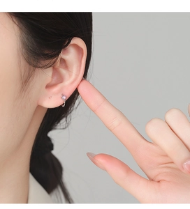 Close-up of a 925 silver earring with a pink round zircon on a female model's ear