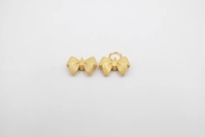 Detailed view of matte gold bow pendants with frosted texture for DIY jewelry making