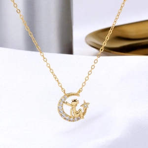 Gros plan détaillé du Petit Prince doré sur un pendentif lune étincelant