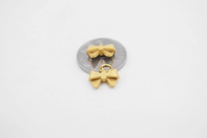 Detail of matte gold bow pendant with S925 hallmark next to a coin for size reference