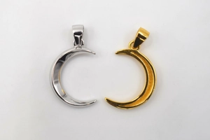 Detailed view of crescent moon pendants in polished silver and golden finishes