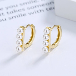 Detail of gold-plated silver huggie earrings with four inlaid white pearls in a row