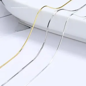 Detailed view of polished gold and silver snake chains on a white ceramic tray