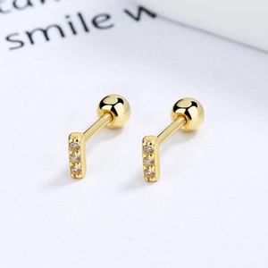 Macro detail of gold 925 silver barbell studs with three vertically inlaid zircons