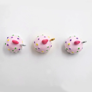 Three pieces of pink enamel cupcake charms with colorful dots and metal hanging loops