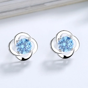 Macro shot of S925 sterling silver four-leaf clover stud earring with blue crystal