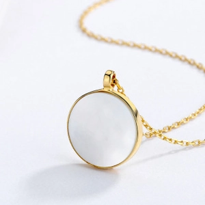 Detailed view of a gold-plated necklace featuring a round white mother of pearl pendant