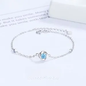 Macro detail of silver four-leaf clover bracelet with blue gemstone and extension chain