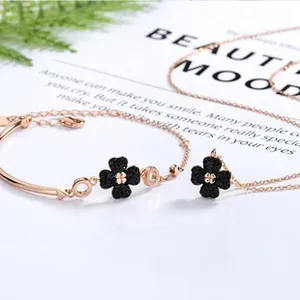 Detail of rose gold clover jewelry set with black clover motifs on a magazine background