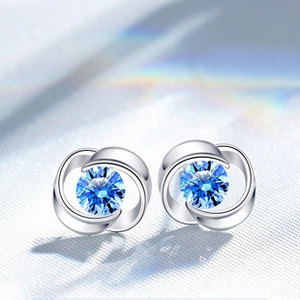 Macro view of S925 silver clover earrings with sparkling round blue sapphire stones