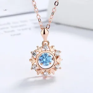 Detail of rose gold snowflake pendant with sparkling blue stone and micro-pave crystals