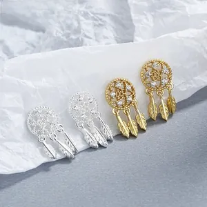Macro detail of silver and gold dreamcatcher earrings with feathers and cubic zirconia
