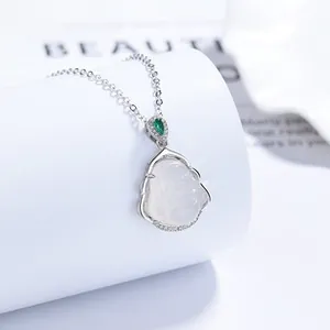 Macro view of sterling silver necklace with Buddha pendant and green emerald teardrop
