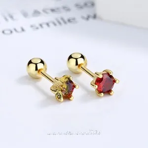 Detailed macro view of six-prong gold earrings with red round stone and screw back closure
