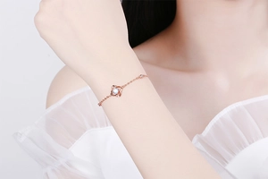 Detailansicht eines rosévergoldeten S925 Silberarmbands mit blauem Kleeblatt auf dem Handgelenk