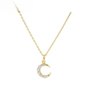 Macro shot of gold crescent moon pendant with pave-set shimmering crystals on fine chain