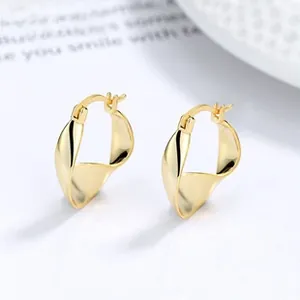 Macro shot of minimalist gold twisted hoop earrings with a polished vintage texture