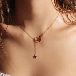 Close-up of rose gold crescent moon and star pendant necklace on model collarbone