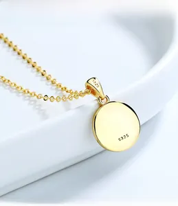 Gros plan du pendentif rond en argent S925 doré avec gravure de poinçon sur le bord