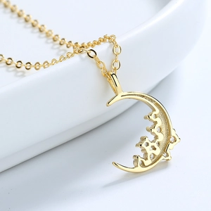 Elegant gold crescent moon pendant necklace with crystal zircons on a white porcelain edge