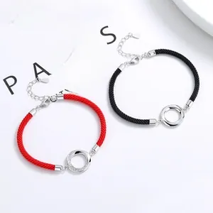 Detail of red and black woven couple bracelets with 100 languages projection and silver ring