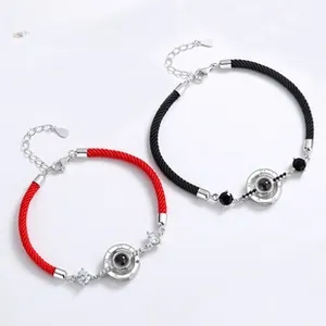 Macro shot of 925 silver projection stone charms on red and black braided cord bracelets