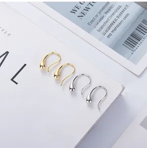 Detail view of minimalist teardrop ear hooks in polished gold and silver finishes