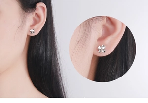 Detail view of silver four-leaf clover stud earring on model with a macro close-up circle