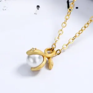 Macro detail of a matte gold pearl pendant with a vine design and a small diamond