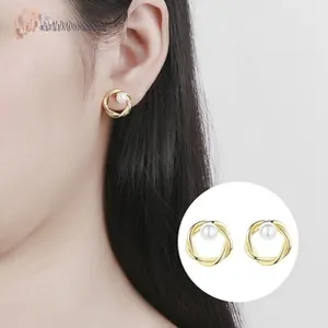 Detail of twisted gold ring earring with a center white pearl on a model's ear