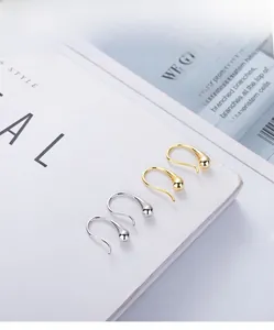 Polished gold and silver teardrop hook earrings displayed on a white magazine background